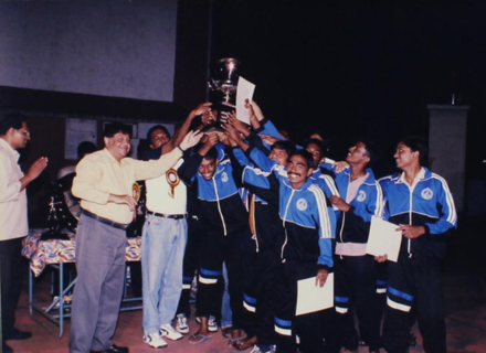 A group of ecstatic students lift a trophy, 1999