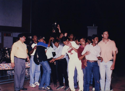 An elated group of students lift a trophy, 1999